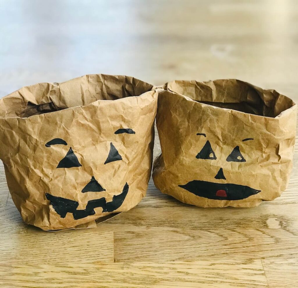 Geniale Halloween Deko basteln: 5 nachhaltige & einfache Ideen 7 Zwei braune Papiertüten umgekrempelt und bemalt als Kürbis Snackschalen für Halloween Party Deko.